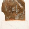 “Door de mechanica”. Kleine bronzen figuur met witmarmeren voetstukje. Achteraan gesigneerd en genummerd 37/100.
