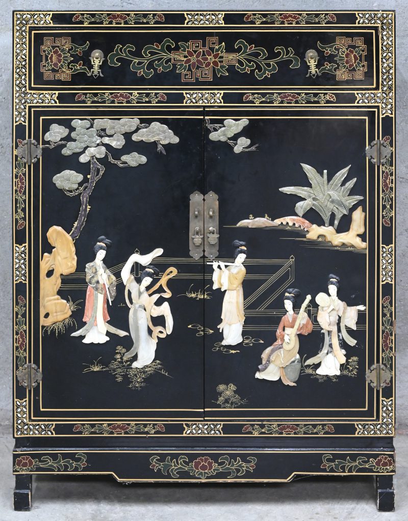 Een zwartgelakt Chinees tweedeurskastje met een lade. De deuren en zijkanten versierd met decors van pietradura.