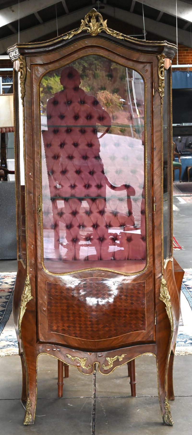 Een Louis XV vitrinekastje op leunhoogte in gefineerd notenhout met marketterie-inlegwerk van ruiten in fruithout onderaan de beglaasde deur, verguld bronzen beslag, gewelfde schuine pootjes.