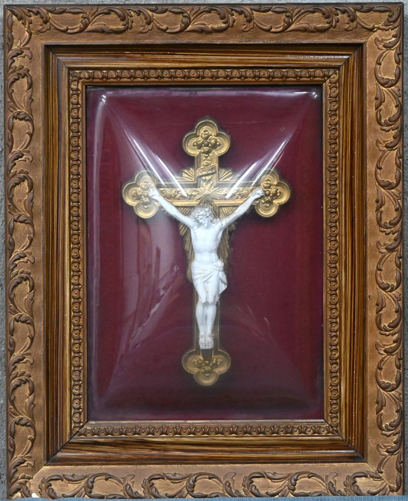 Een houten kader met plaasteren Christusbeeld onder bol glas.