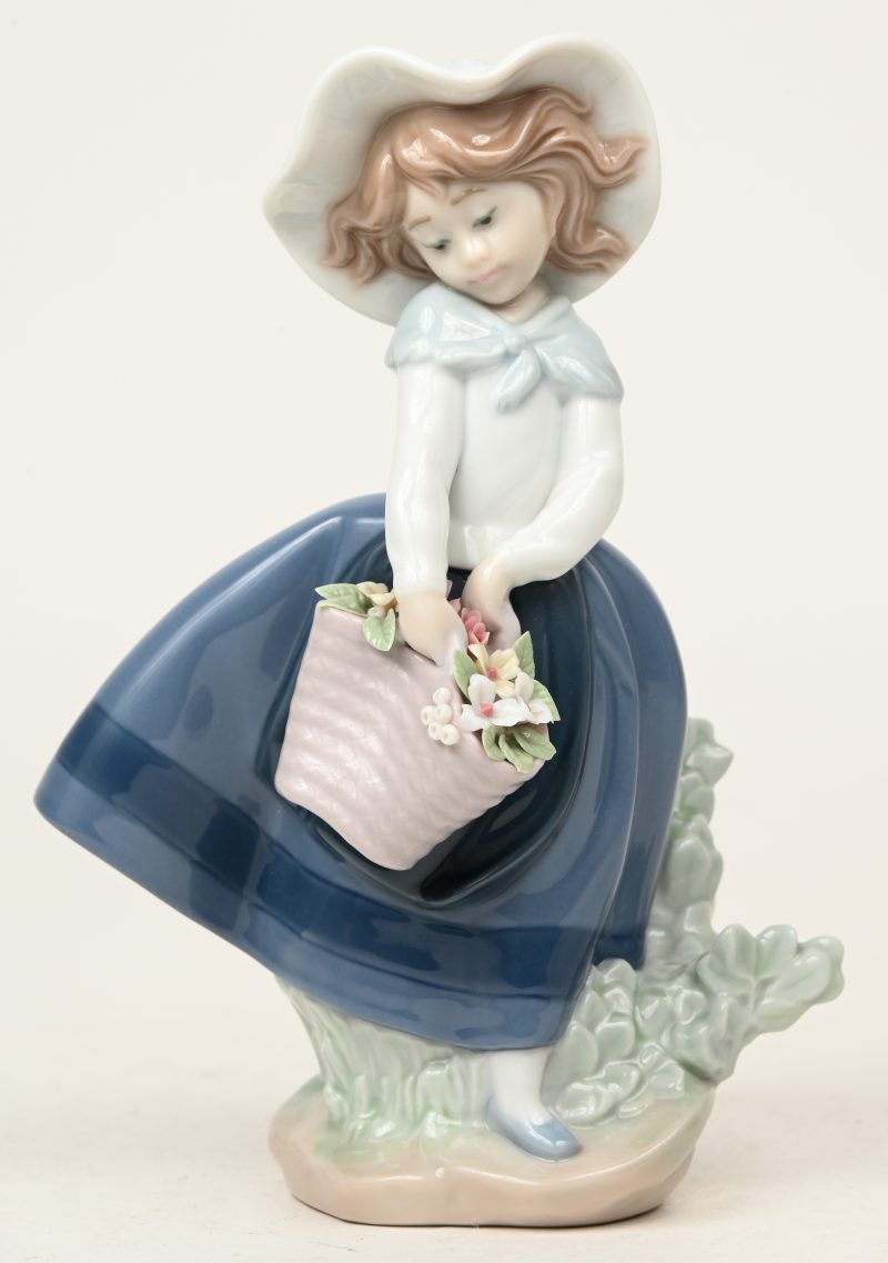 “Meisje met bloemenmand”. Een beeldje van meerkleurig Spaans porselein. Gemerkt en gedateerd 1983.