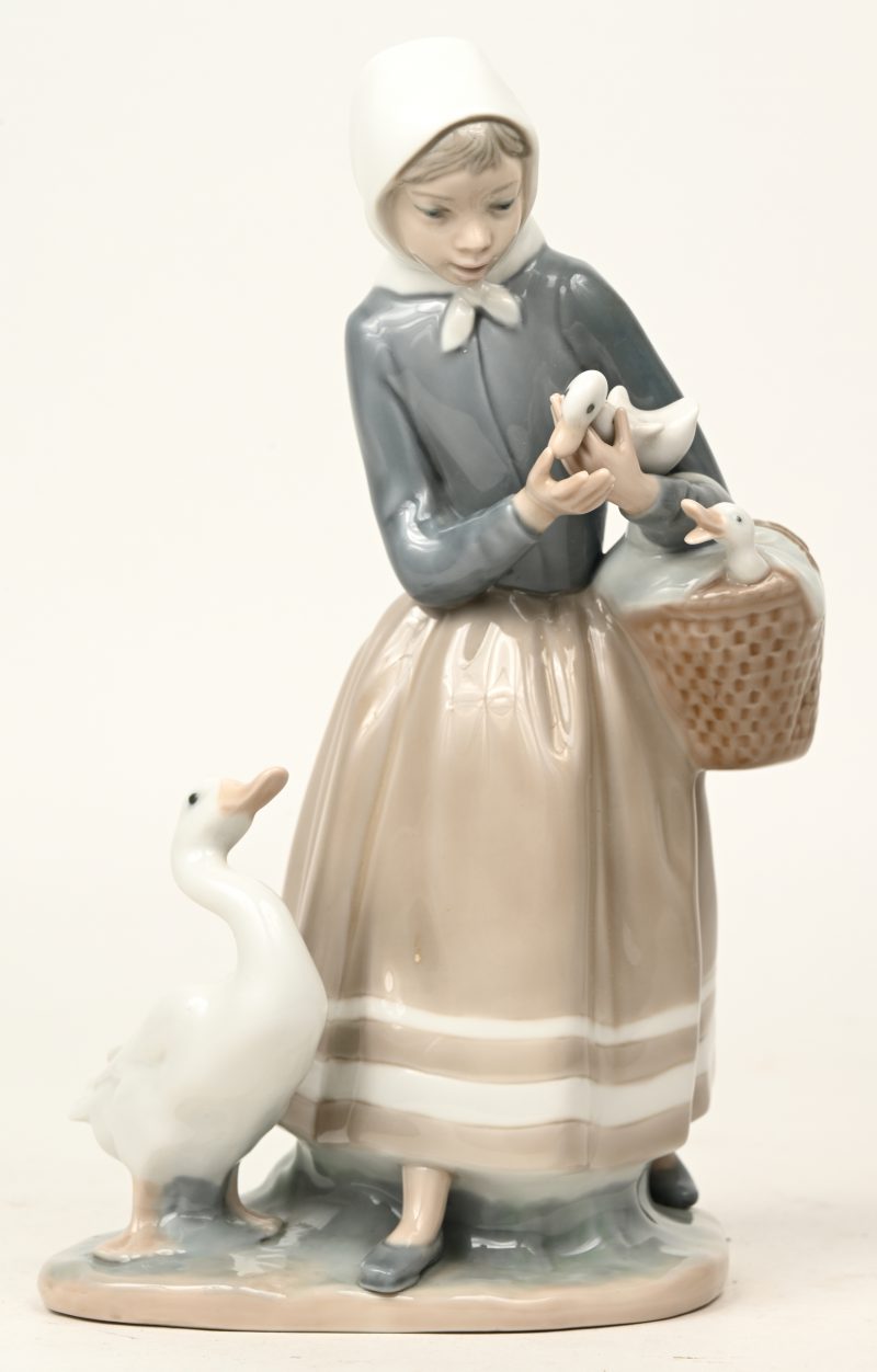 “Jongen vrouw met eenden”. Een beeldje van meerkleurig Spaans porselein. Onderaan gemerkt.