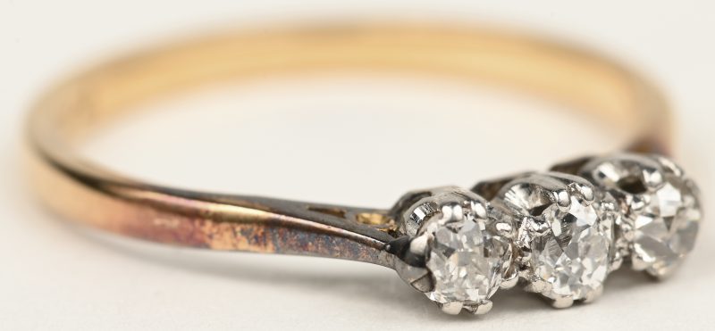 Een 18 K wit en geelgouden ring bezet met drie briljanten met een gezamenlijk gewicht van +- 0,30 ct.