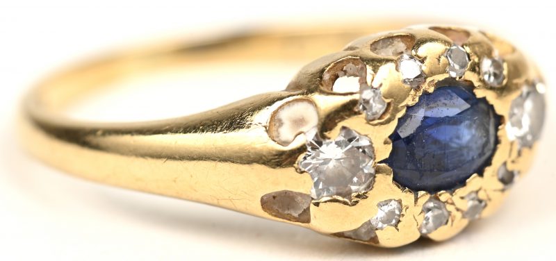 Een 18 K wit-en geelgouden ring bezet met drie briljanten met een gezamenlijk gewicht van +- 0,20 ct. en een saffier van +- 0,20 ct.