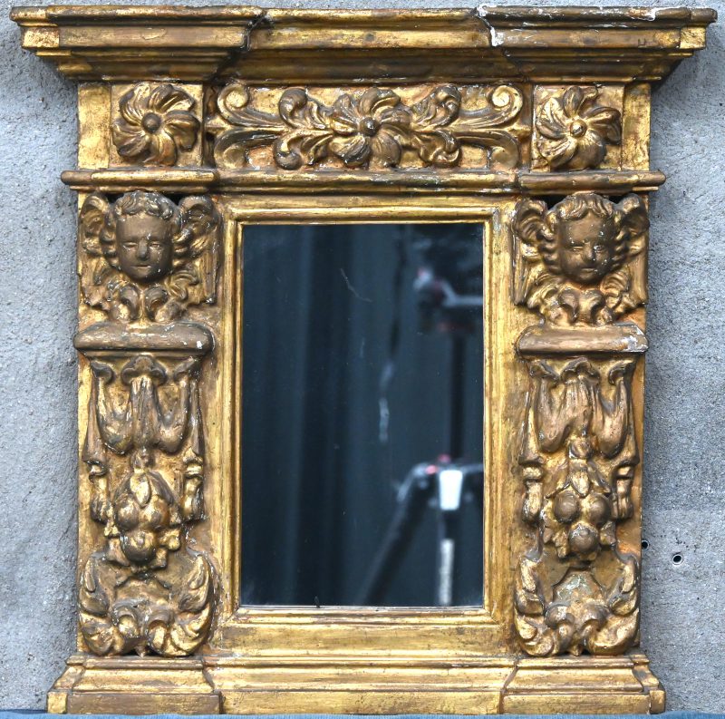 Een antieke spiegel in vergulde lijst.