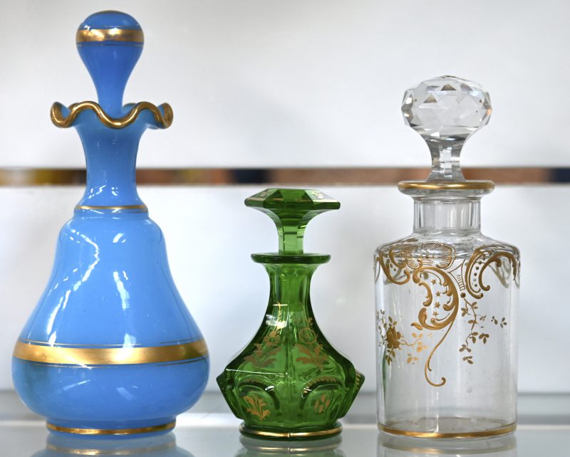 Een lot van drie verschillende glazen parfumflesjes met handgeschilderde gouden decoraties.