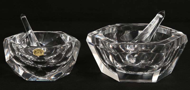 Twee zeshoekige asbakken van geslepen kleurloos kristal, beide met stamper. Gemerkt onderaan. Eén met kleine schilfer aan de binnenrand.