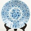 Een blauw witte schotel met bloemendecor op drie pootjes van Delfts porselein.