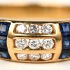 Een 18 K geelgouden ring bezet met diamanten en safier en smaragd baguettes met een gezamenlijk gewicht van +- 0,80 ct.