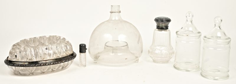 Een lot kleurloos glaswerk, bestaande uit een windlicht, twee bokalen en een pique-fleur en twee parfumflesjes met verzilverde monturen.