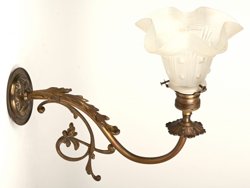 Een messingen wandlampje met gesatineerd glazen kapje. Begin XXe eeuw.