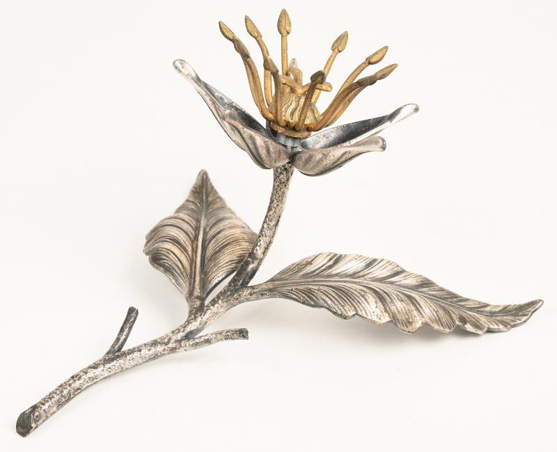 Een metalen sierstuk met tweekleurig patina in de vorm van een bloem. Onderaan gesigneerd.