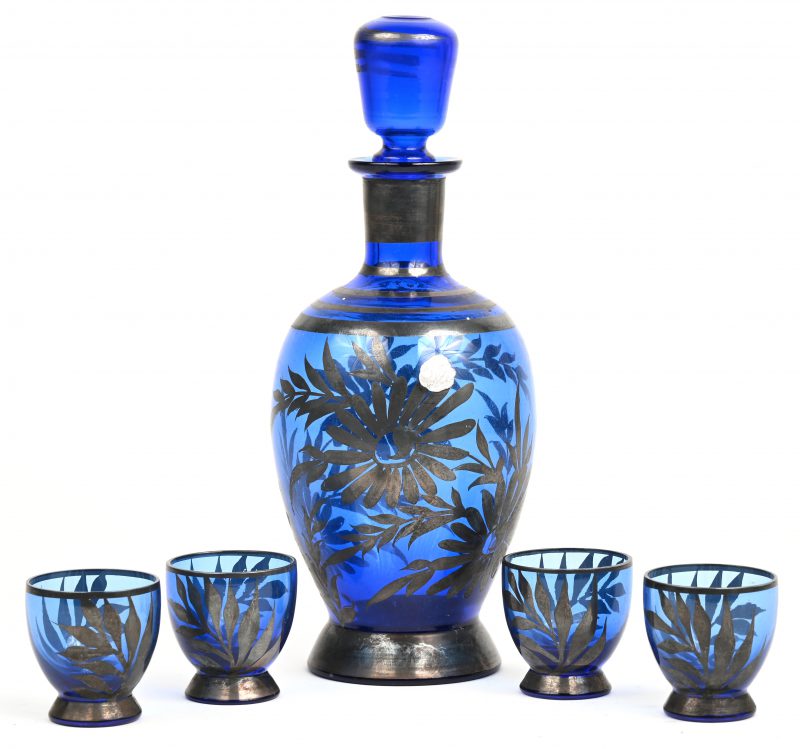 Een antiek blauw glazen karafje met vier bijpassende borrelglaasjes, beschilderd met zilveren bloemendecor.