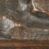 “Zittend naakt met geitje”. Een groep van deels gepatineerd en deels verzilverd brons op houten voetstuk. Gesigneerd en met stempel.