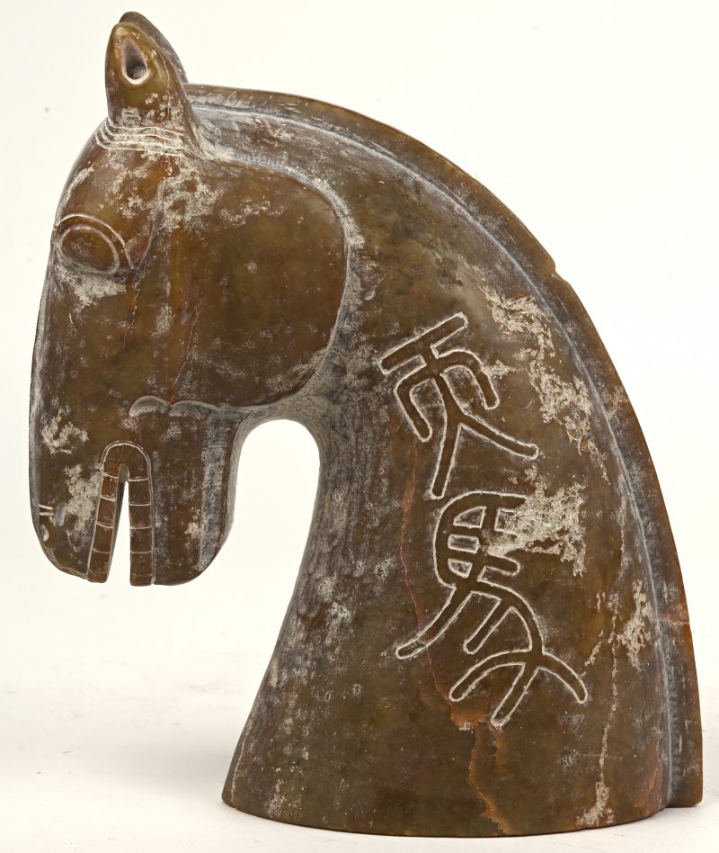 Een beeldje van een gestyleerde paardenkop van gebeeldhouwd steen, naar de voorbeelden van de Tang Dynastie (VIIe-IXe eeuw).