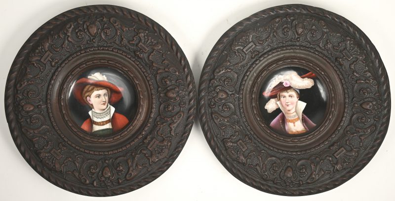Een paar schotels met handgeschilderde damesportretten op porselein met gedreven koperen boord. XIXe eeuw.