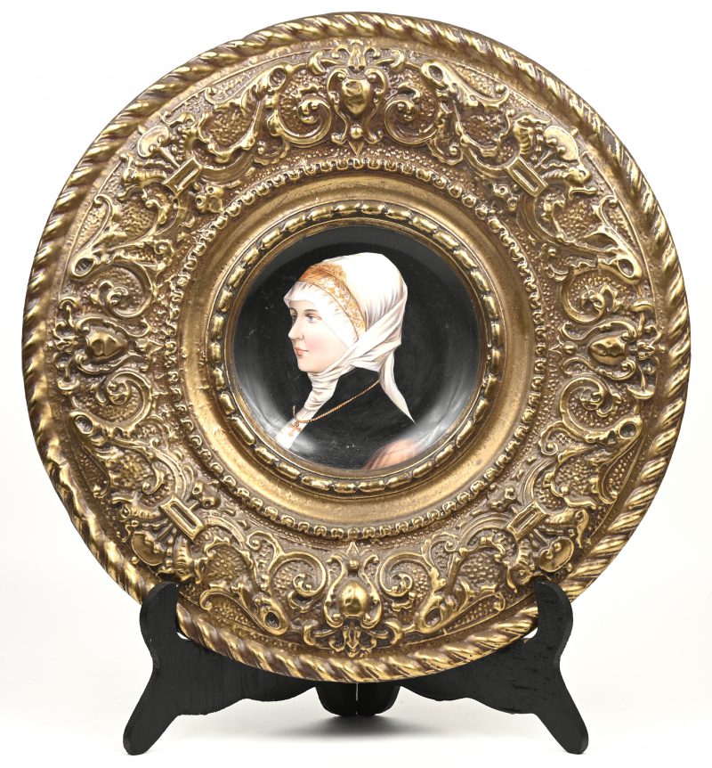 Een sierschotel met een damesportret op porselein in gedreven messingen boord.
