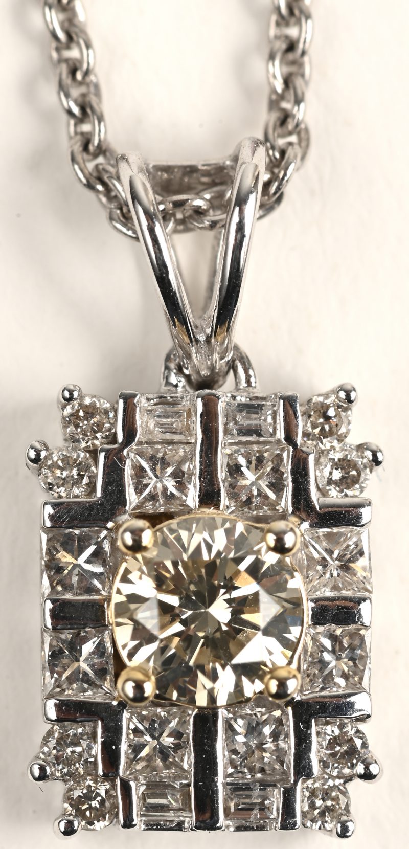 Een 18 K witgouden ketting met 18 K wit en geelgouden hanger bezet met een centrale briljant van +- 0,40 ct. en diamant baguetten en markiezen met een gezamenlijk gewicht van +- 0,39 ct.