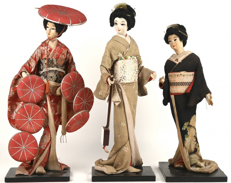 Drie verschillende Japanse geishapoppen op houten voetstukken. Japanse volkskunst.