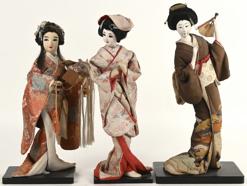 Drie verschillende Japanse geishapoppen op houten voetstukken. Japanse volkskunst.