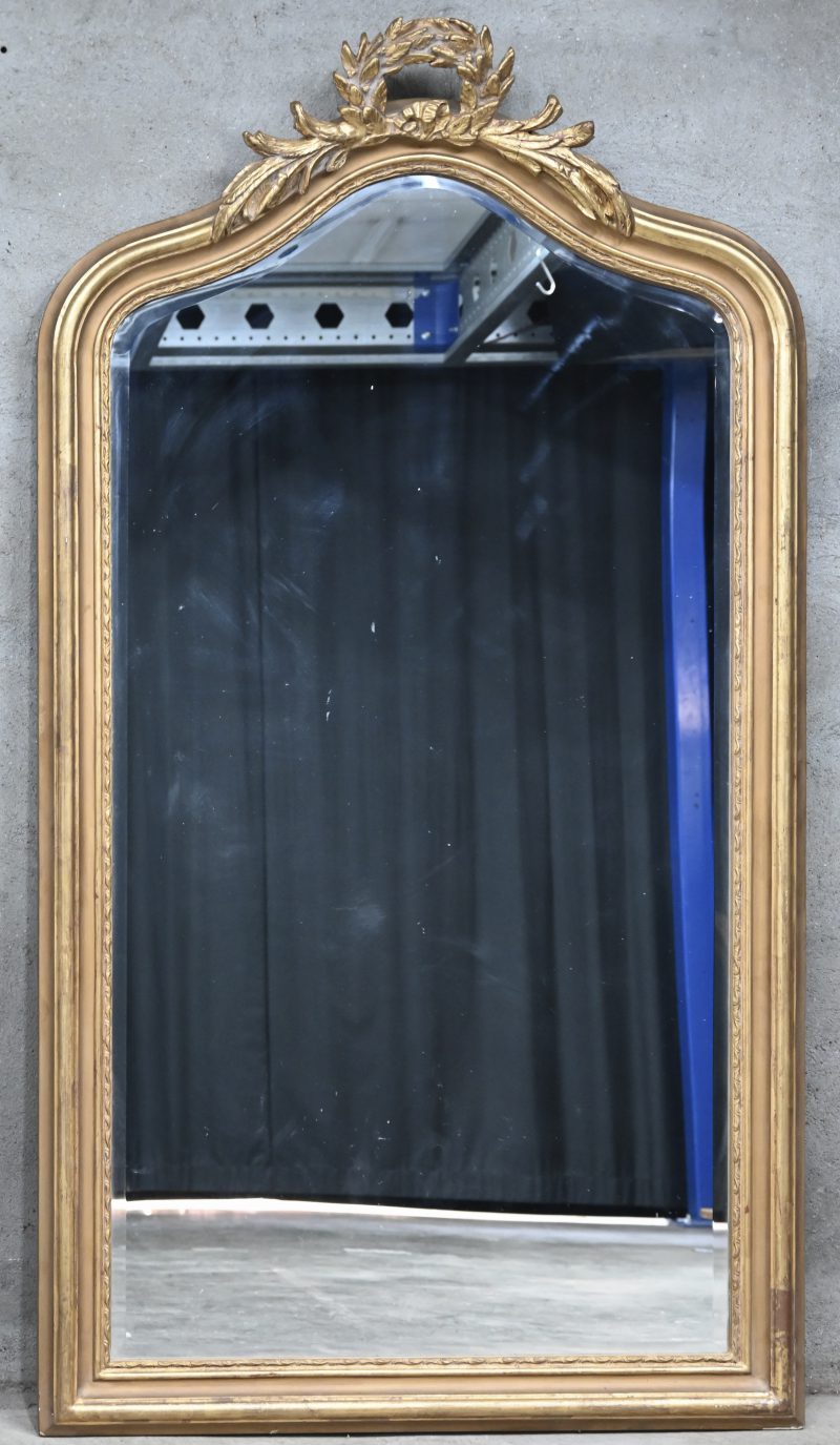 Een vergulde houten spiegel in Louis-Philippestijl met een lauwerkrans in de kuif.