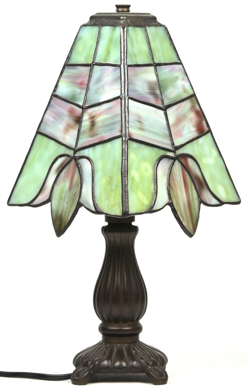 Een klein bronzen lampje met een vierhoekig kapje van glas in lood.