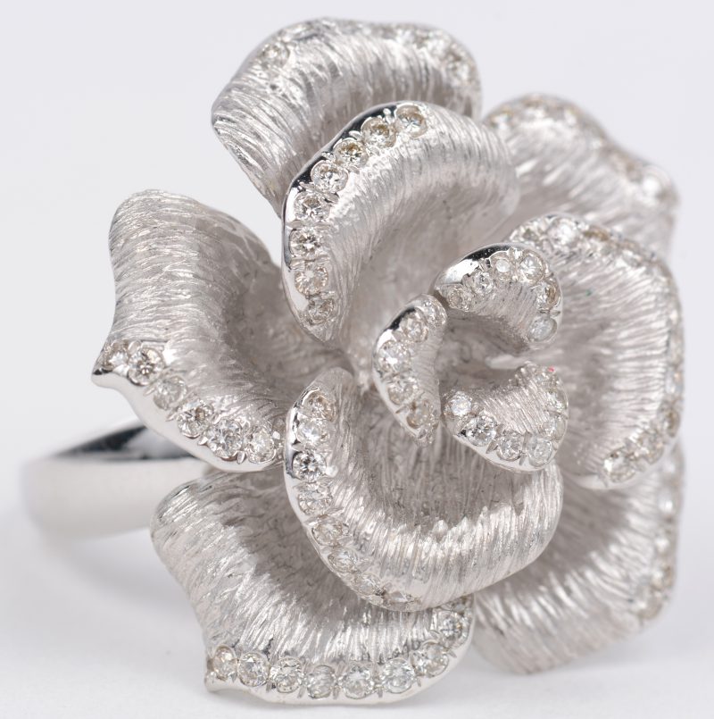 Een 18 karaats wit gouden ring in de vorm van een roos, aan de rand bezet met diamanten met een gezamenlijk gewicht van ± 0,70 ct.