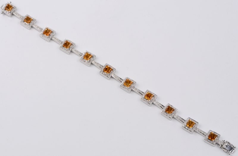 Een 18 karaats wit gouden schakelarmband bezet met diamanten met een gezamenlijk gewicht van ± 1 ct. en citrine met een gezamenlijk gewicht van ± 10 ct.