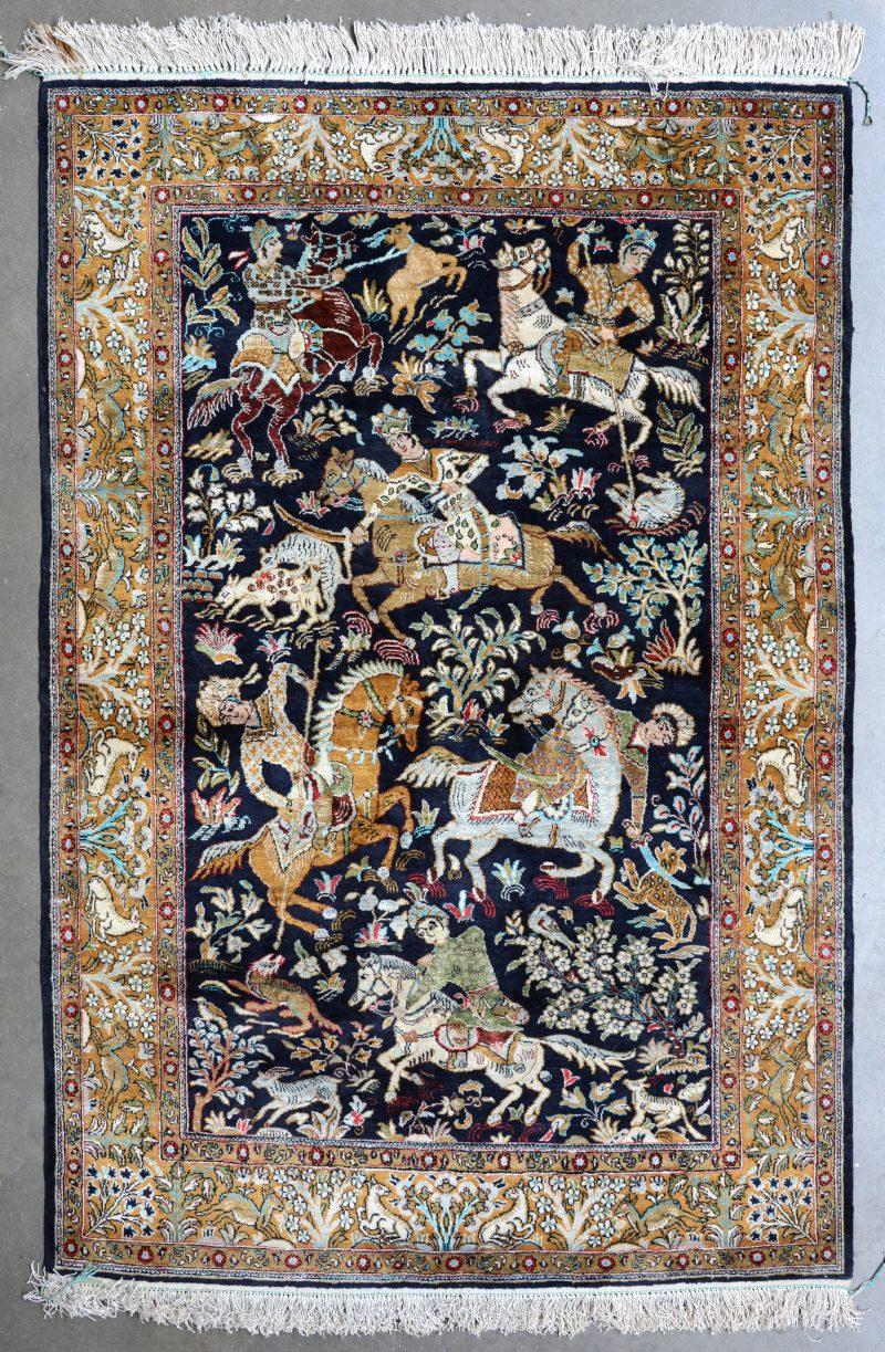 Een handgeknoopt Perzisch kleedje van zijde met een jachtscène in het decor.