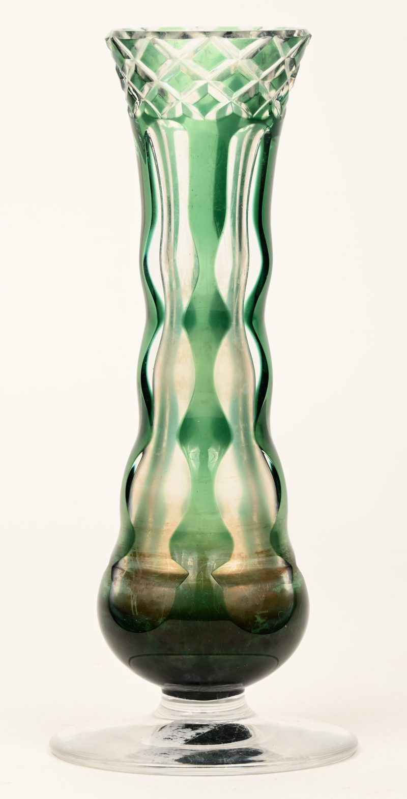 Een soliflorevaasje op ronde voet van geslepen kristal, in de massa groen gekleurd. Onderaan gemerkt.
