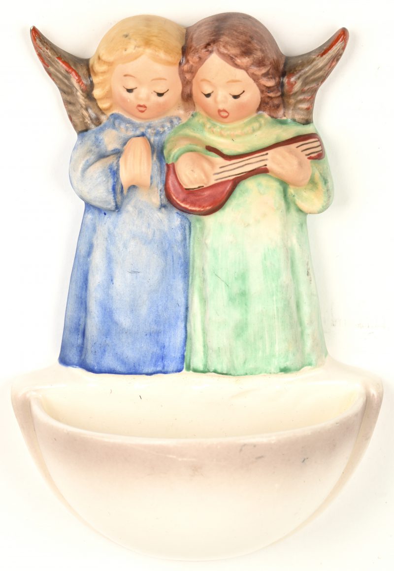 Een meerkleurig biscuit wijwatervaatje met beeltenis van twee zingende engeltjes. Ontwerp van M.I. Hummel. Gemerkt en genummerd 146.