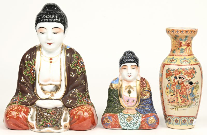 Twee zittende Boeddha’s van meerkleurig Japans porselein. Onderaan gemerkt. We voegen er een kleine Japanse balustervaasje aan toe.