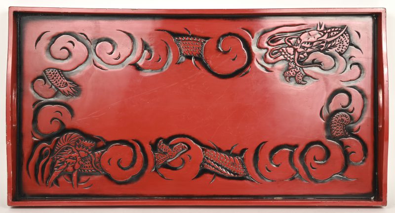 Een roodgelakt Chinees houten dienblad met een drakendecor.