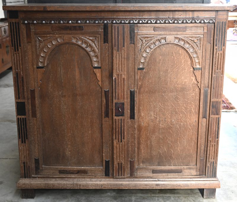 Een eikenhouten meubel met gesculpteerde versieringen in en rond de twee deuren.