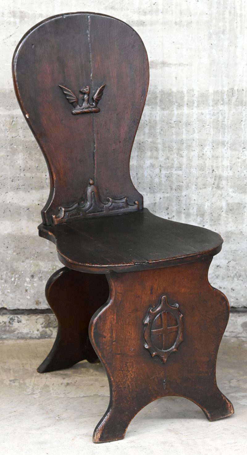Een Engelse sgabellostijl hallstoel van eikenhout, versierd met een roofvogel op de rug en een Engels kruis op de poot.Omstreeks 1800.