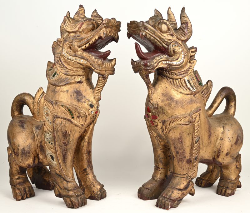 Een paar vergulde houten fo honden met decoratie van gekleurd glas.