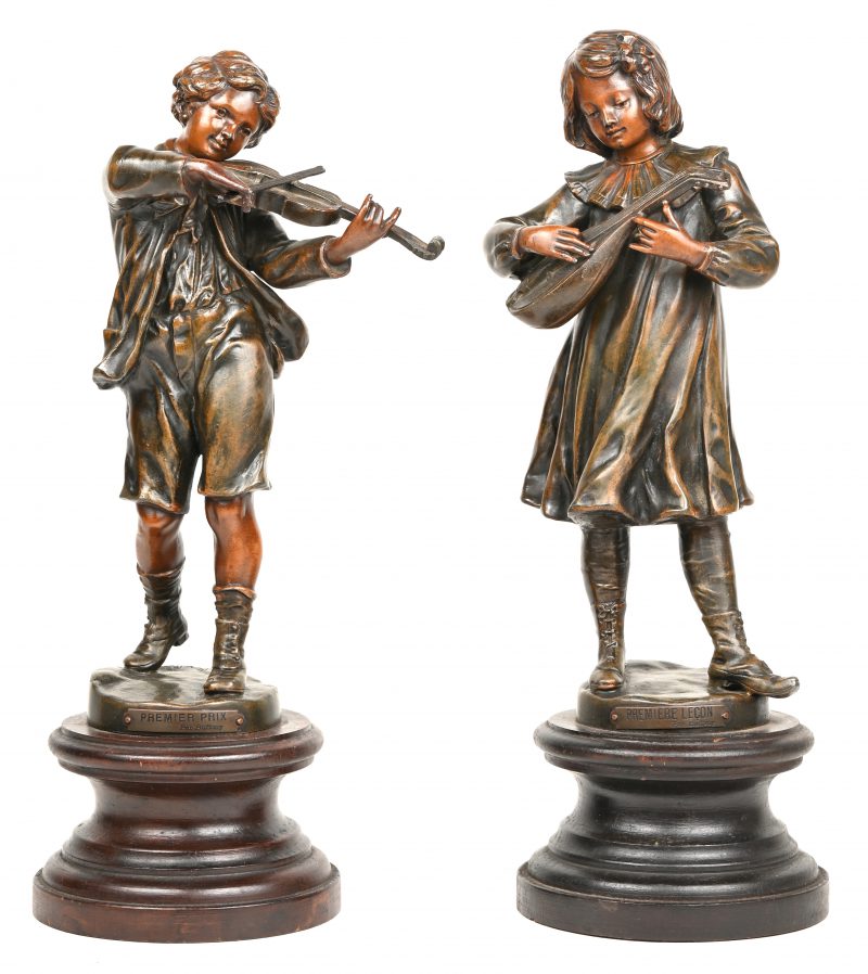 “Première prix de violon” & “Leçon de guitare”. Twee zamakken beeldjes op houten voetstukken. Naar Oscar Ruffony. Jaren ‘30.