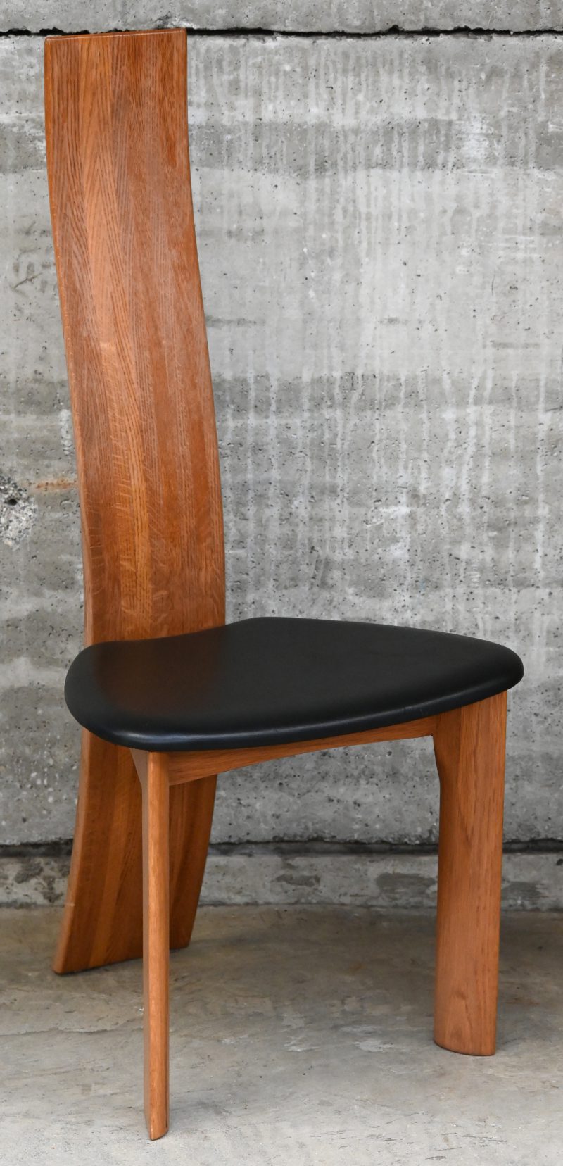 Een design stoel met zwarte bekleding. Naar het model Golem van Vico Magistretti (1969).