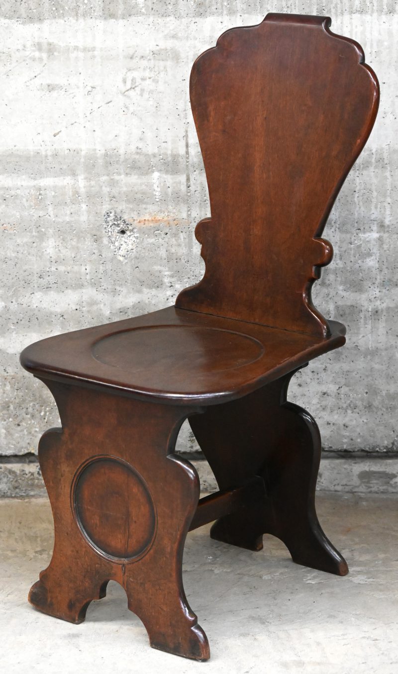 Een donkere houten stoel in sgabellostijl.