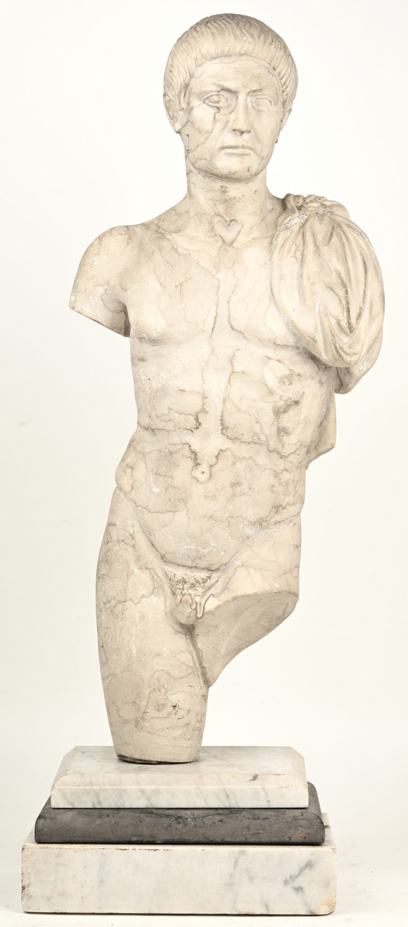 “Romeinse figuur.” Stenen sculptuur op marmeren voet. Genummerd 1165. Draagt monogram. Enkele kleine beschadigingen.