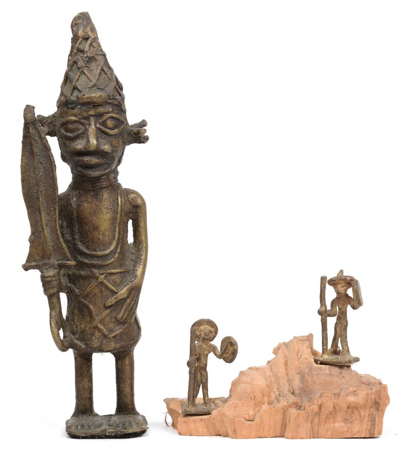 Drie bronzen beeldjes, waarbij twee miniatuur op houten voetstukje en een groter beeldje van een krijger. Benin.