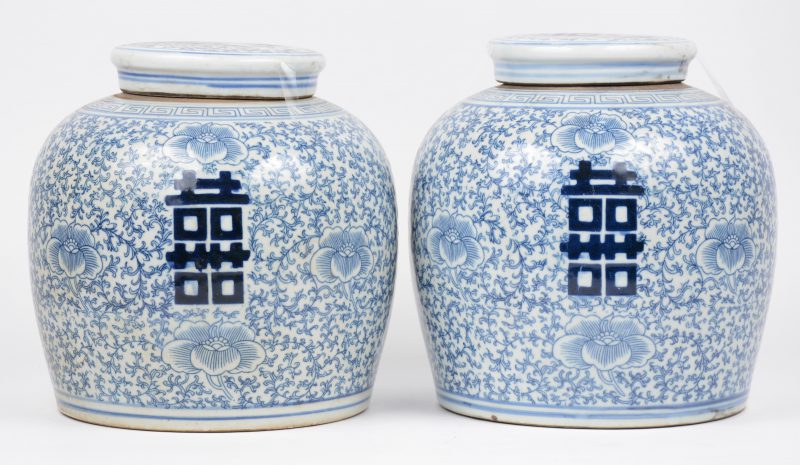 Een paar gemberpotten van Chinees porselein met een blauw op wit decor van tekens op een achtergrond van vegetale motieven.