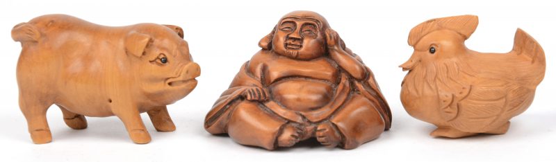 Een netsuke in de vorm van een Boeddha, erotische voorstelling, van tropisch hardhout. We voegen er nog twee houten netsuke’s in de vorm van een varken en een kip aan toe.