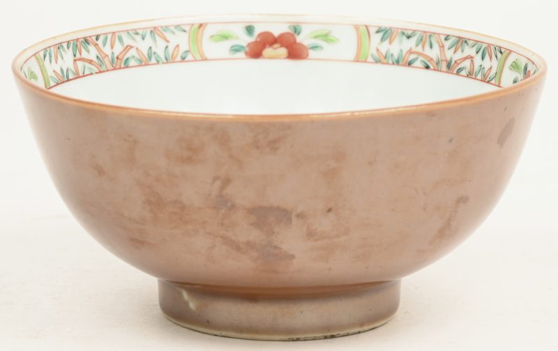 Een kleine Capucine bowl van Chinees porselein met binnenin een famille rose landschapdecor, buiten chocoladebruin gekleurd. Omstreeks 1800.