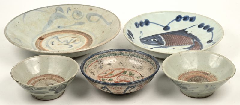 Drie diverse schotels van Chinees aardewerk met blauw en roestrode versiering. Lichte schade (haarscheuren) en slijtage.