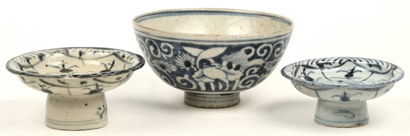 Drie stuks antiek Chinees porselein met een blauw en wit decor, bestaande uit twee kleine tazza’s op voet (het grootste met kleine letsels) en een bowl (Ø 15 cm) met een decor van vogels en bloemen (haarscheur).