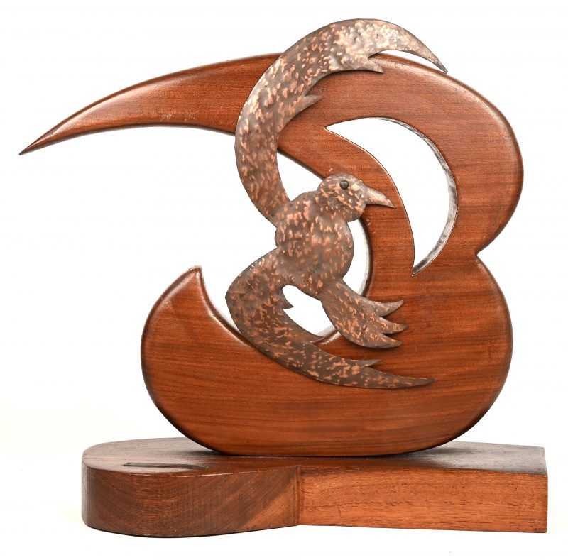 Een kunstwerk van hout en metaal met een stormvogel in de wind. Gemonogrammeerd B.R.