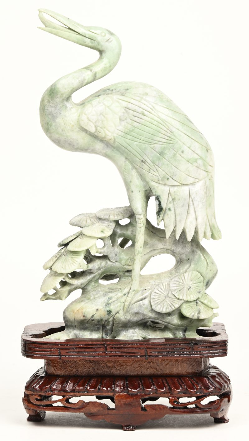 Een kraanvogel van gesculpteerd jadeiet op houten sokkeltje. Chinees werk.