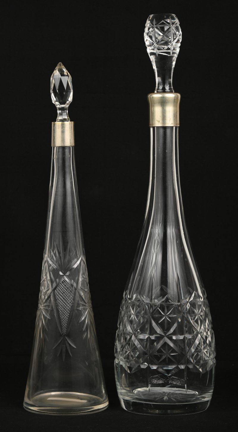 Twee elegante karaffen van geslepen glas met verzilverd metalen bovenranden.