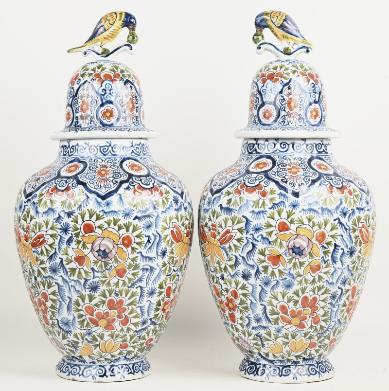 Een paar aardewerken dekselvazen met meerkleurige bloemendecors en de deksels getooid met vogels. Onderaan gemerkt. Frankrijk, eind XIX-eeuw. Eén staartje beschadigd.